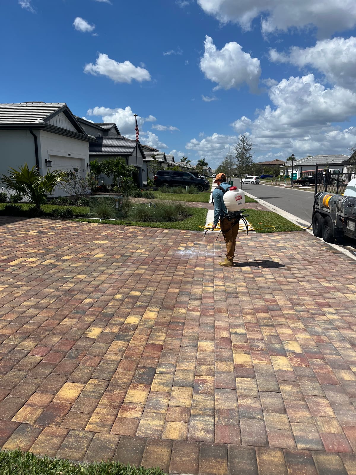 Technician soft washing a brick paver driveway